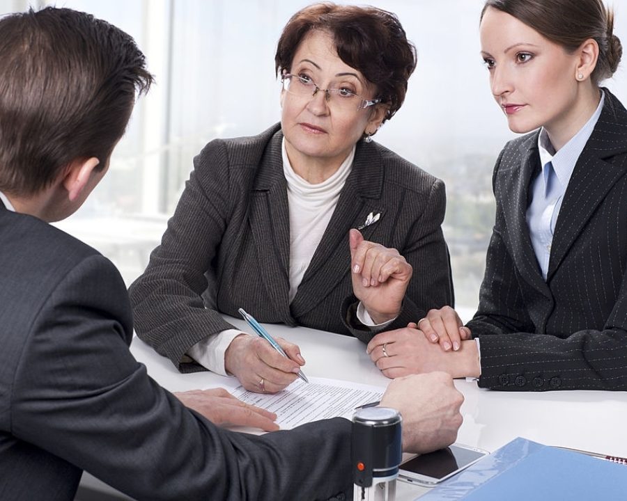 Agent (or notary public) signing documents with with senior woman and her daughter